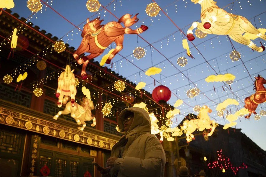 Una mujer camina bajo faroles que adornan una calle para el pr&oacute;ximo A&ntilde;o Nuevo Chino, o A&ntilde;o Nuevo Lunar, en Pek&iacute;n