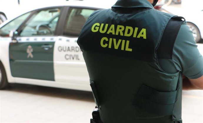 Archivo - Agente de la Guardia Civil junto a un veh&iacute;culo del instituto armado