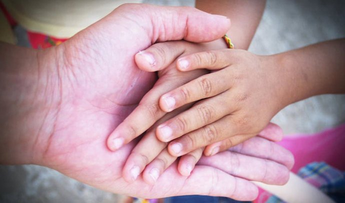 Archivo - Manos de ni&ntilde;o y adulto.